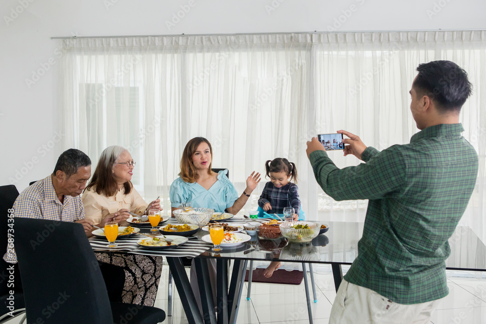 Young man takes photo his family in dining table