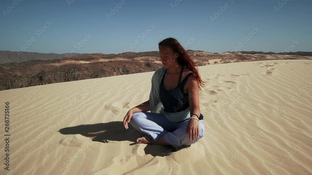 Handsome female have meditation on sand dune in desert slow motion Handsome female have meditation on sand dune in desert slow motion