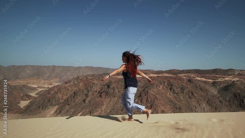 Handsome female extatic running on sand dune in desert slow motion Handsome female extatic running on sand dune in desert slow motion