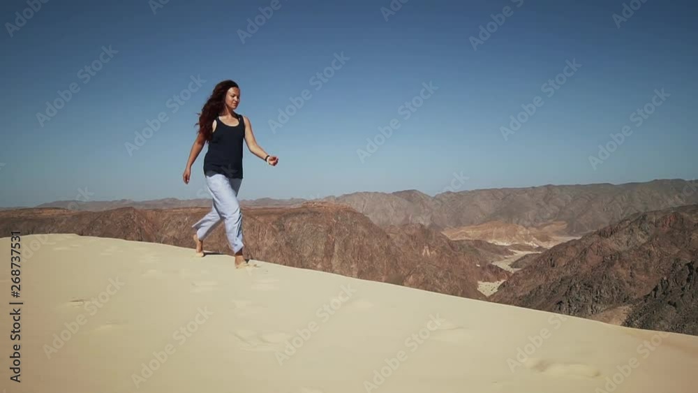 Handsome female extatic running on sand dune in desert slow motion Handsome female extatic running on sand dune in desert slow motion
