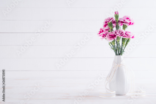 Fototapeta Naklejka Na Ścianę i Meble -  Valentines day and love concept. Pink carnation flower in vase on white wooden background.
