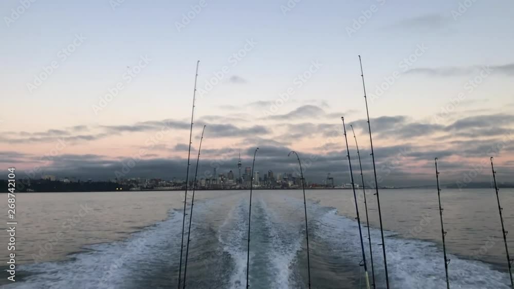 SLOW MOTION - Back of fishing boat with fishing rods leaving Auckland city out to sea SLOW MOTION - Back of fishing boat with fishing rods leaving Auckland city out to sea