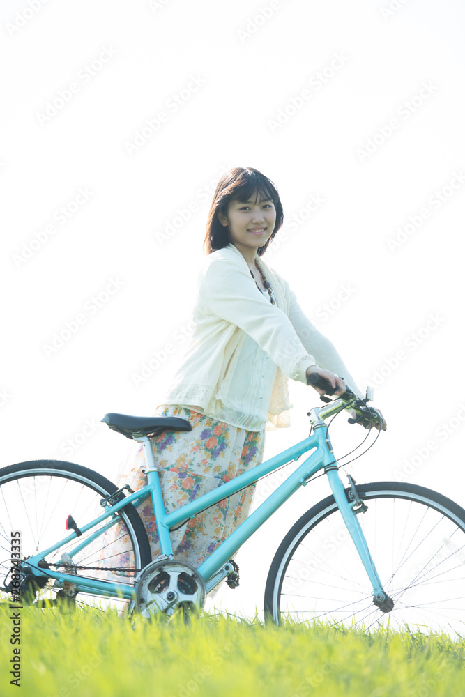 Obraz premium 草原で自転車を押す女性