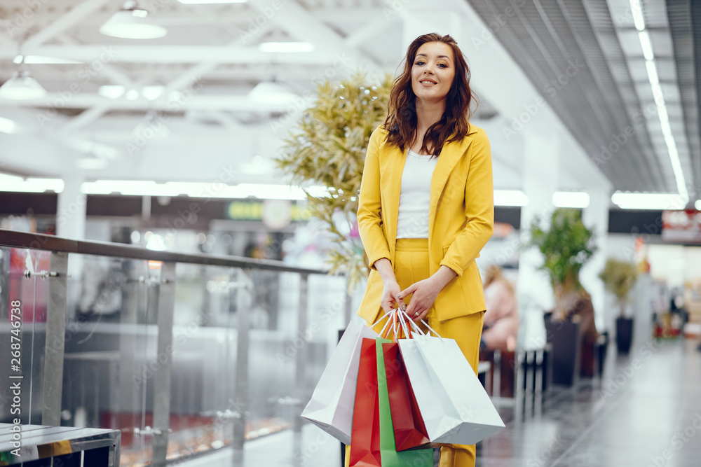 Beautiful girl in a summer city. Lady with shopping bags. Woman in a yellow suit