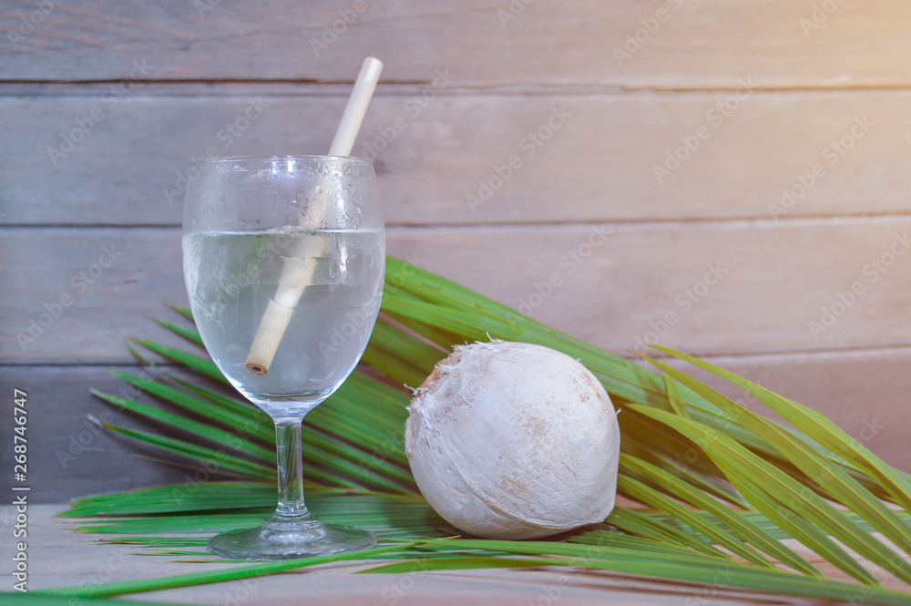 Coconut water in a glass on a wooden floor Coconut water in a glass on a wooden floor