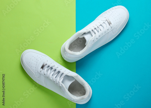 Fashionable white sneakers on a two-tone background. Top view