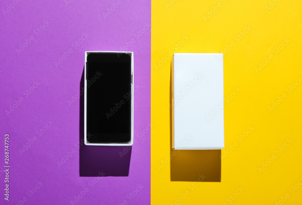 New smartphone in open box on colored paper background. Top view, minimalism New smartphone in open box on colored paper background. Top view, minimalism
