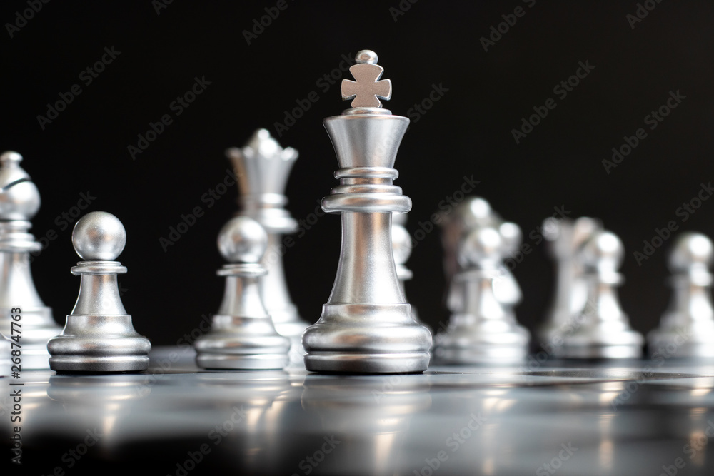 Silver king chess piece stand in front of team on black background (Concept for leadership, management) Silver king chess piece stand in front of team on black background (Concept for leadership, management)