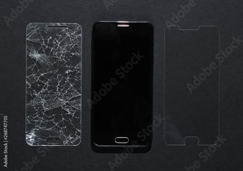 Fotografia Smartphone with broken and new protective glass on black background