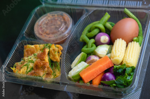 Various kinds of blanched vegetables, omelet, cha-am, and chili paste beautifully arranged in clear plastic boxes. and look modern