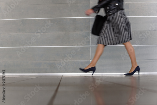 Closeup of elegant busy woman walking on gray background