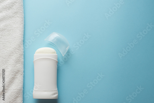 Deodorant and towel , body care flat lay on blue background with copy space