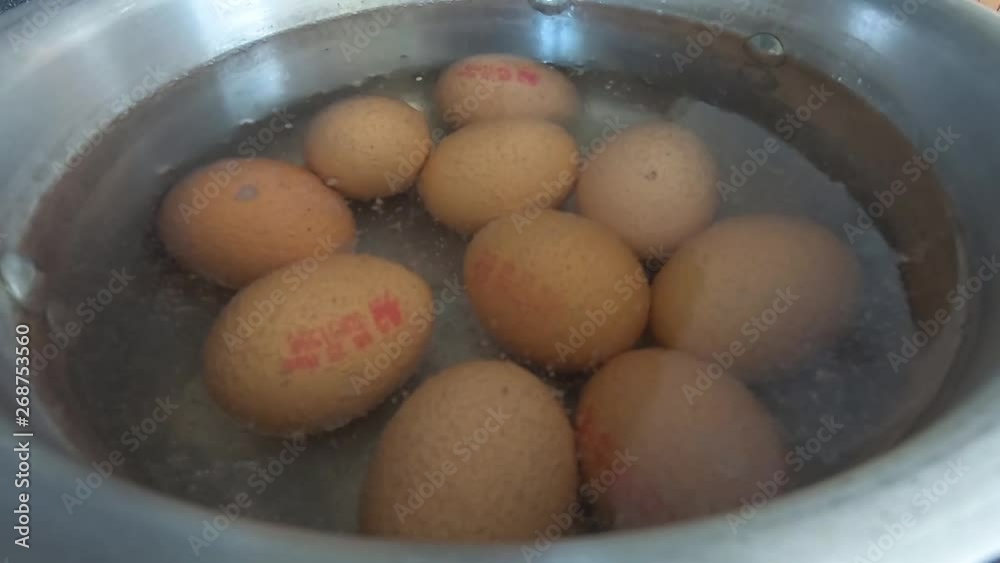 Close up of 10 eggs slowly coming to boil in water in a silver pot pan in a kitchen Close up of 10 eggs slowly coming to boil in water in a silver pot pan in a kitchen