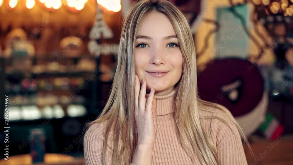 Portrait of a beautiful blonde girl in a cozy coffee shop, she is looking at the camera and smiling Portrait of a beautiful blonde girl in a cozy coffee shop, she is looking at the camera and smiling