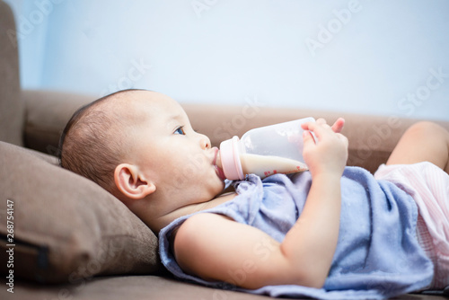 baby feeding bottle - Closeup portrait of asia child hold milk bottle and feeding on sofa bed