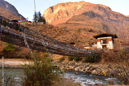 side view of walking suspension bridge with a lot of colorful prayer flags in Bhutan. photo