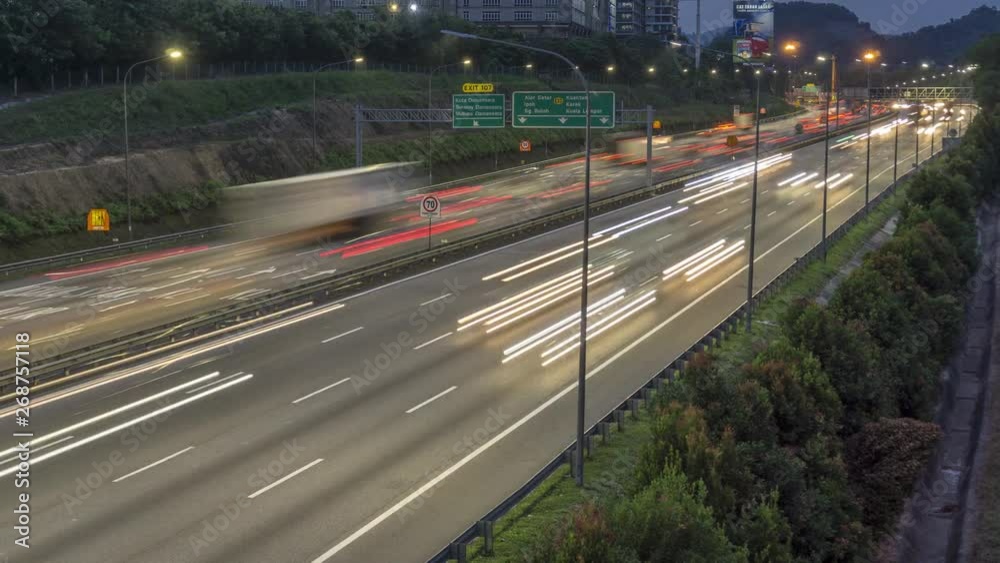 Panning timelapse of traffic light trails on highway at dusk.
