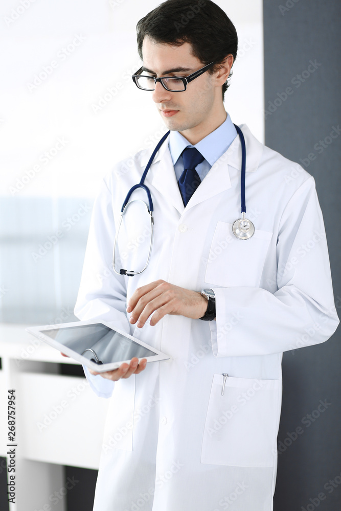 Doctor man using tablet computer for network research or virtual disease treatment. Perfect medical service in clinic. Modern medicine, medic data and healthcare concepts Doctor man using tablet computer for network research or virtual disease treatment. Perfect medical service in clinic. Modern medicine, medic data and healthcare concepts