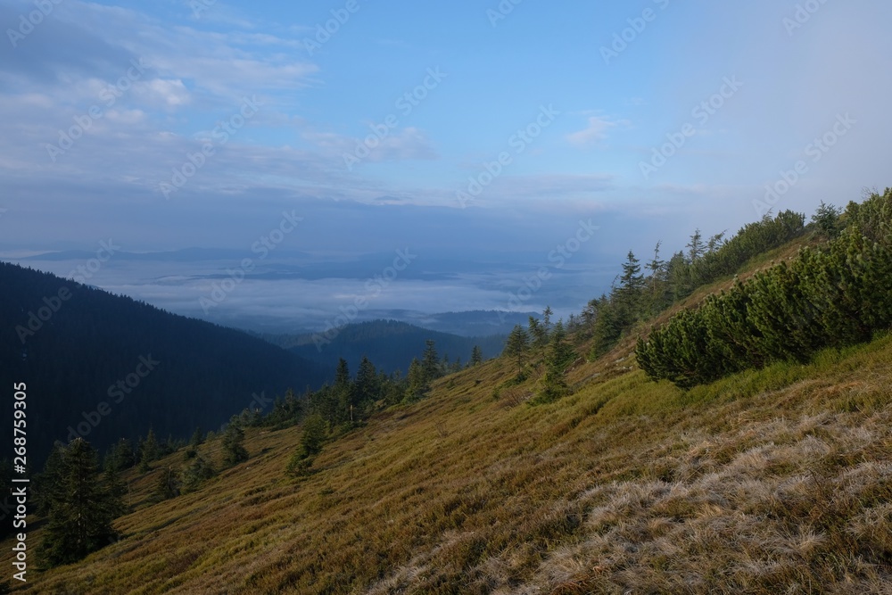 Babia Gora - mountain range in Beskid Zywiecki during spring with fog, clouds and sun