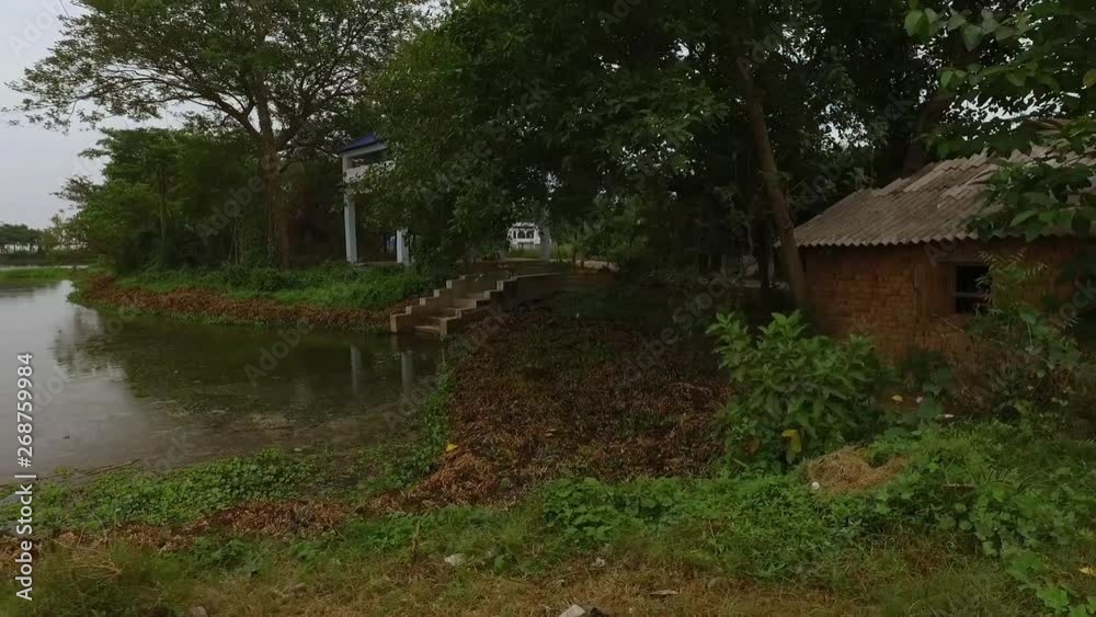 A dolly, medium shot of a pond and a little old house built near it.