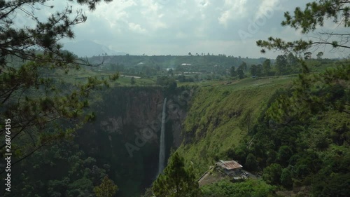 Rotating pan of Sipiso Piso, one of the tallest waterfall in Indonesia, and the lush green fields surrounding the crest of the waterfall. photo