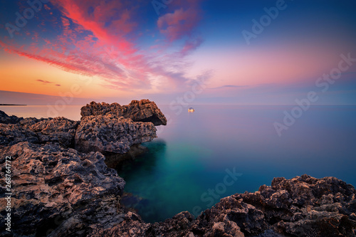Amazing sunset image of Cape Greco cliffs and rocks on a sunset in Paralimni, Cyprus. Colorful red, pink and yellow skies with turquoise blue sea.  photo