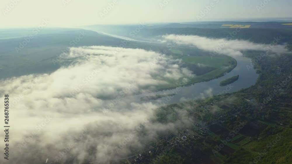 Slowly looking up over a river Dniester and small village covered in mist in the morning sun.