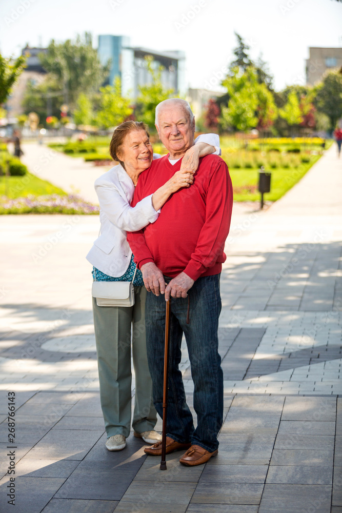 Cheerful senior couple having good time in city park, walking, laughing and enjoying sunny day