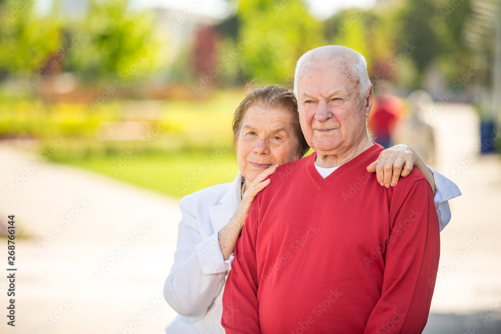 Cheerful senior couple having good time in city park, walking, laughing and enjoying sunny day