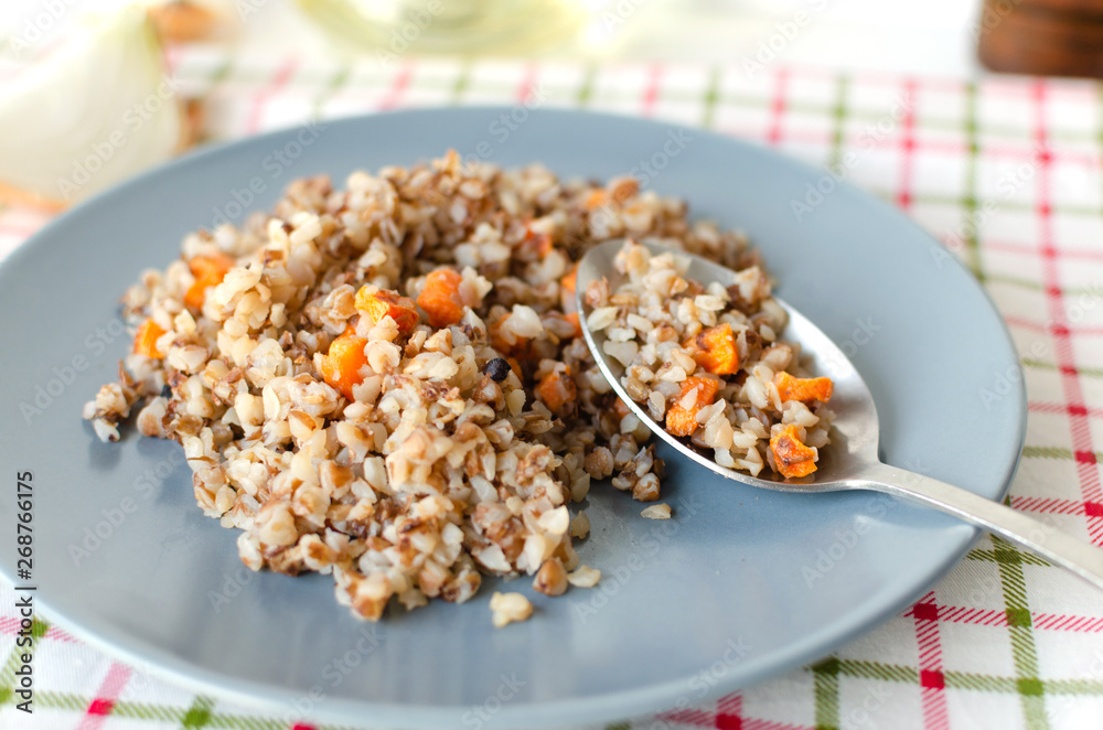 Buckwheat porridge in a gray plate on a background of a checkered napkin. Healthy food. Buckwheat porridge in a gray plate on a background of a checkered napkin. Healthy food.