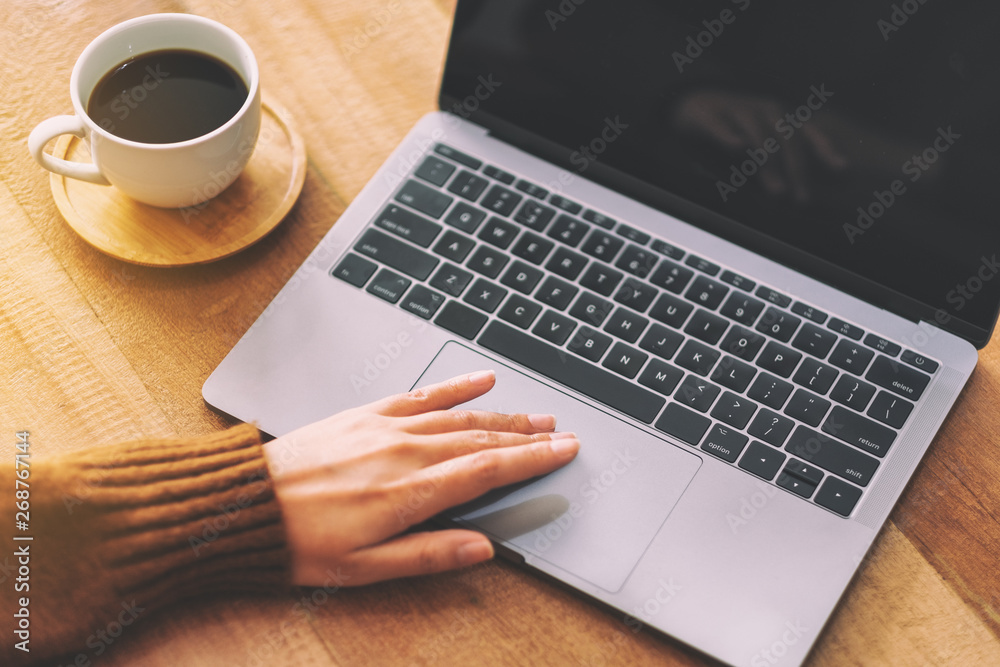 Closeup image of a woman's hand using and touching on laptop touchpad on wooden table Closeup image of a woman's hand using and touching on laptop touchpad on wooden table