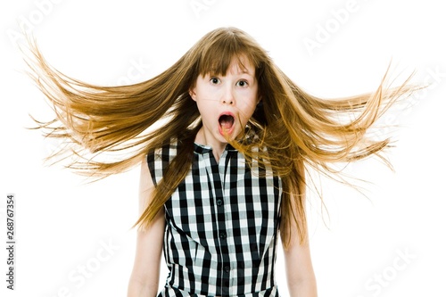 Surprised teenaged girl with long straight flying hairs wear black checkered dress.