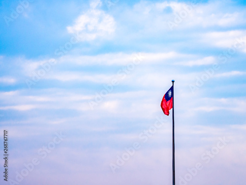 Closeup Taiwan nation flag waving on a pole with colorful pastel sky and clouds.
