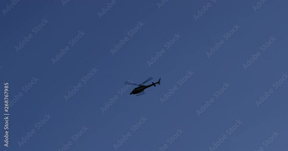 Silhouette of a helicopter flying overhead in the sky with bright puffy clouds. Shot in 4k slow motion.mov Silhouette of a helicopter flying overhead in the sky with bright puffy clouds. Shot in 4k slow motion.mov
