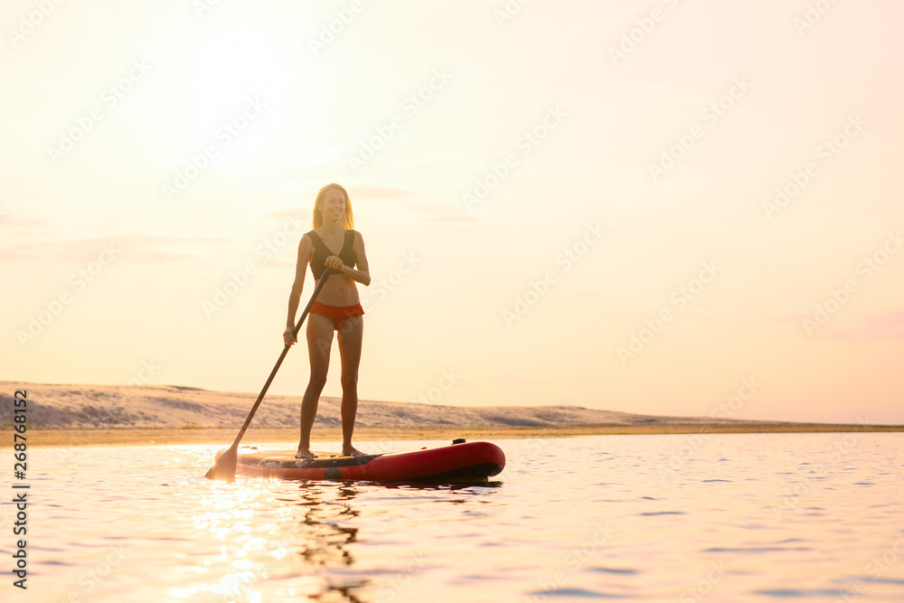 Silhouette of woman standing on paddle board