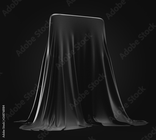 Smartphone prototype hidden under black cloth cover on dark background photo