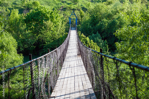Fototapeta Naklejka Na Ścianę i Meble -  Old suspension bridge on the background of fresh greens