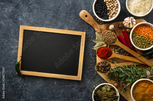 Fototapeta Naklejka Na Ścianę i Meble -  Chalkboard with spices and herbs top view with rice, various beans on dark background. Menu background