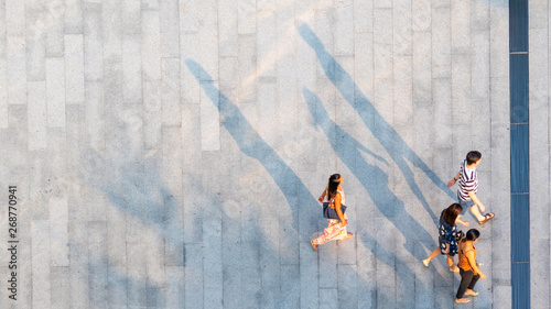 group of people walk on across the pedestrian concrete landscape in the city street (Aerial top view)