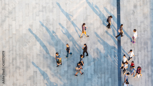 group of people walk on across the pedestrian concrete landscape in the city street (Aerial top view)