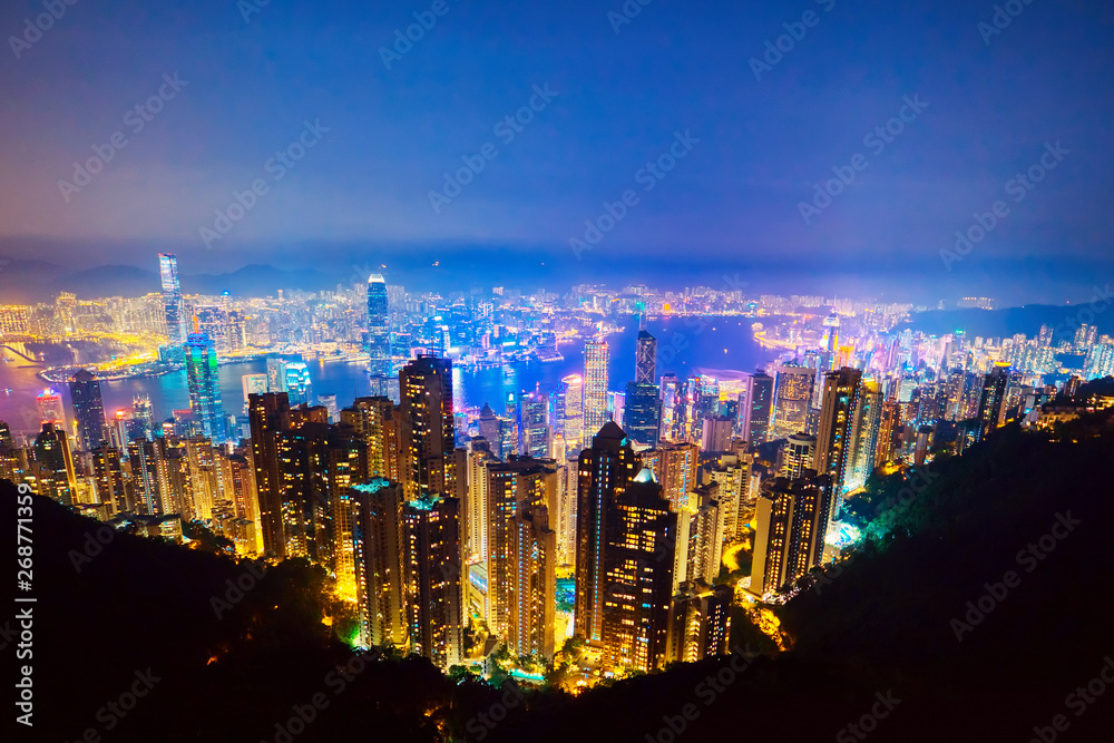 Obraz premium The most famous view of Hong Kong at twilight sunset. Hong Kong skyscrapers skyline cityscape view from Victoria Peak illuminated in the evening. Hong Kong, special administrative region in China.