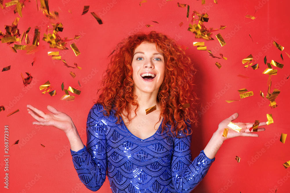 Beautiful redhead woman and falling confetti on color background Beautiful redhead woman and falling confetti on color background