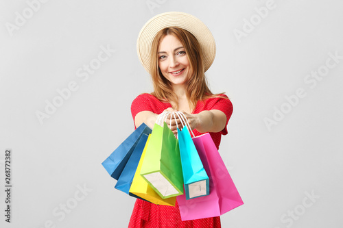 Portrait of mature woman with shopping bags on light background