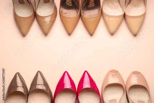 Different stylish high heeled shoes on color background
