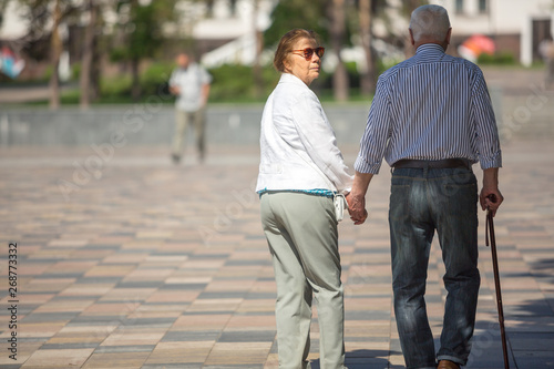 Senior adults walking in a park holding hands