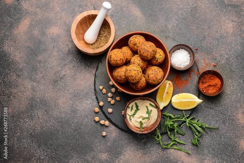 Bowl with tasty falafel balls and sauce on grey background