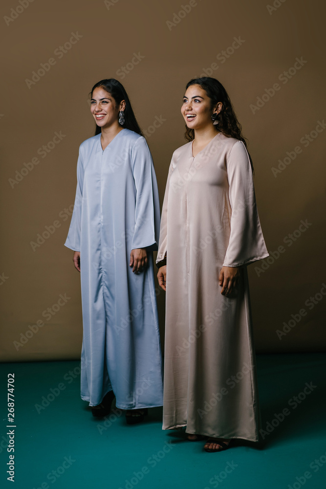 Portrait of two young Middle Eastern Muslim women smiling as they pose for their photo. They are wearing traditional pastel coloured Baju Kurung dresses to visit during Raya. Portrait of two young Middle Eastern Muslim women smiling as they pose for their photo. They are wearing traditional pastel coloured Baju Kurung dresses to visit during Raya.
