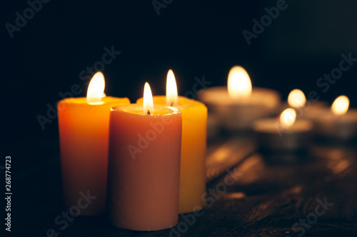 candles burning in darkness over black background. commemoration concept.