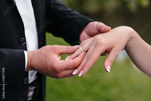 The groom dresses the bride's wedding ring on hand.