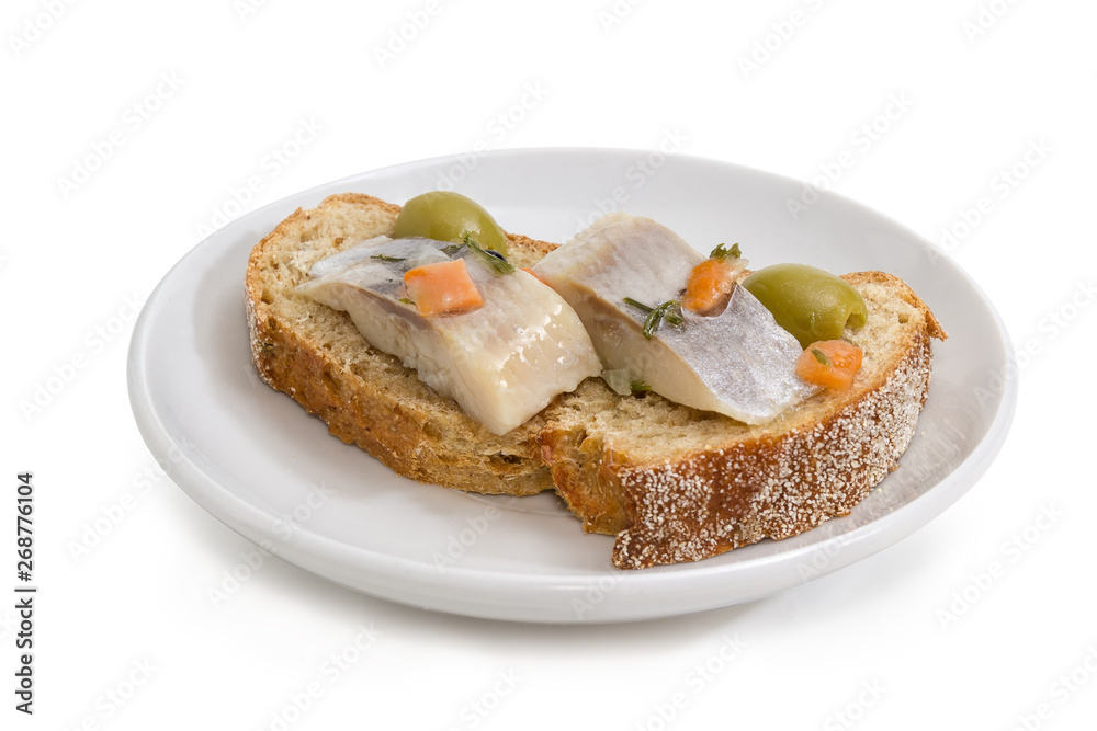 Open sandwich with pickled herring and olives on saucer